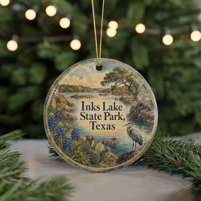 A circular ornament with a scenic landscape of Inks Lake State Park, Texas, featuring a bird, flowers, and a body of water.