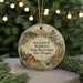 A round ornament with a scenic landscape featuring a cabin, mountains, and a bird, hanging from a string.