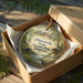 A circular ornament with a scenic image of Johnsonville State Historic Park in Tennessee, displayed in a wooden box with a gold string.