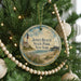 A round ornament hanging on a Christmas tree, featuring a lighthouse and beach scene with the text "Jones Beach State Park, New York".