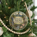 A round ornament hanging on a Christmas tree, featuring a scenic landscape with a waterfall and mountains.