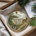 A decorative ornament with a scenic landscape of Knob Noster State Park, Missouri, displayed in a box with pine branches.