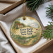A decorative ornament with a rural scene, featuring a farmhouse, a path, and greenery, is displayed in a box.