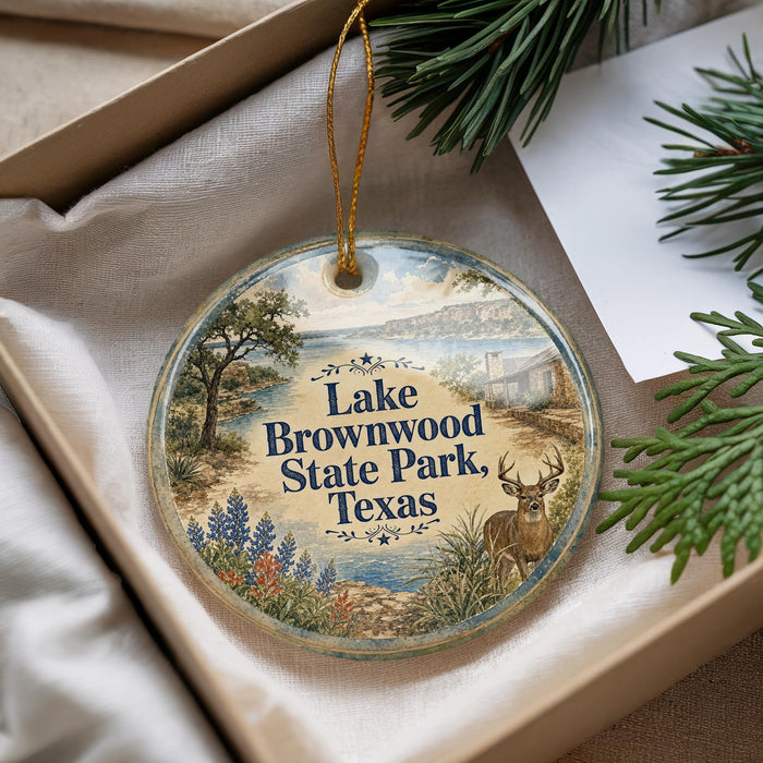 A decorative ornament with a landscape scene featuring Lake Brownwood State Park, Texas, and pine branches.
