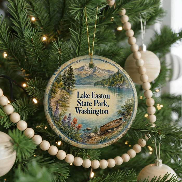 A round ornament hanging on a Christmas tree, featuring a scenic landscape with a lake, mountains, and a boat.