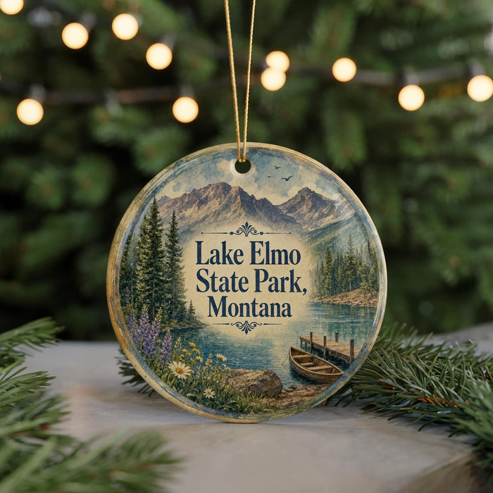 A round ornament with a scenic landscape of Lake Elmo State Park, Montana, featuring a lake, mountains, pine trees, and a boat on the water.