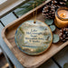 A decorative ornament featuring a scenic landscape of Lake Conaway, Nebraska, with a lighthouse and pine cones on a wooden tray.