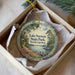 A decorative ornament in a box, featuring a scenic landscape with a lighthouse and a body of water.