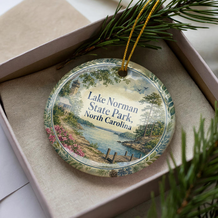A decorative ornament in a box, featuring a scenic image of Lake Norman State Park in North Carolina.