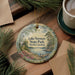 A decorative ornament featuring a scenic landscape of Lake Norman State Park in North Carolina, with a lighthouse and pine trees in the background.