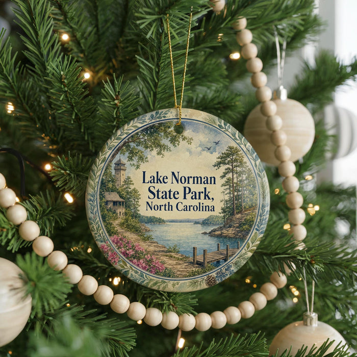 A round ornament hanging on a Christmas tree, featuring a scenic view of Lake Norman State Park in North Carolina.