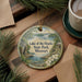 A decorative ornament with a scenic image of Lake of the Ozarks State Park, Missouri, surrounded by pine branches and a cup of coffee on a wooden surface.