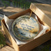 A round ornament in a box, featuring a scenic landscape with a lake, trees, and birds, along with the text "Lake Tawakoni State Park, Texas".