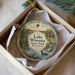 A decorative ornament in a box, featuring a scenic landscape with a lake, trees, and a waterfall.