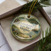 A decorative ornament with a scenic image of a lake, boats, and a bird, along with the text "LESS THAN 500 CHARACTERS" printed on it.