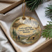A decorative ornament with a scenic landscape of Lewis and Clark State Park, Montana, featuring a river, mountains, and people walking along the trail.