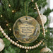 A circular ornament hanging on a Christmas tree, featuring a scenic landscape with a river and mountains.