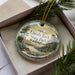 A decorative ornament in a box, featuring a scenic landscape with a lake and mountains, with the text "Lincoln Rock State Park Washington" printed on it.