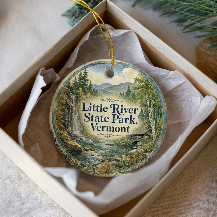 A decorative ornament in a box, featuring a scenic image of Little River State Park in Vermont.