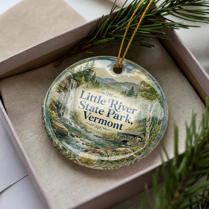A decorative ornament in a box, featuring a scenic image of Little River State Park in Vermont.