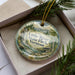 A decorative ornament in a box, featuring a scenic image of Little River State Park in Vermont.