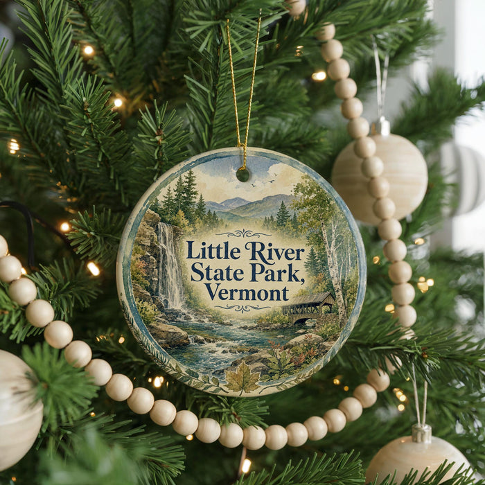 A round ornament on a Christmas tree, featuring a scenic image of Little River State Park in Vermont.