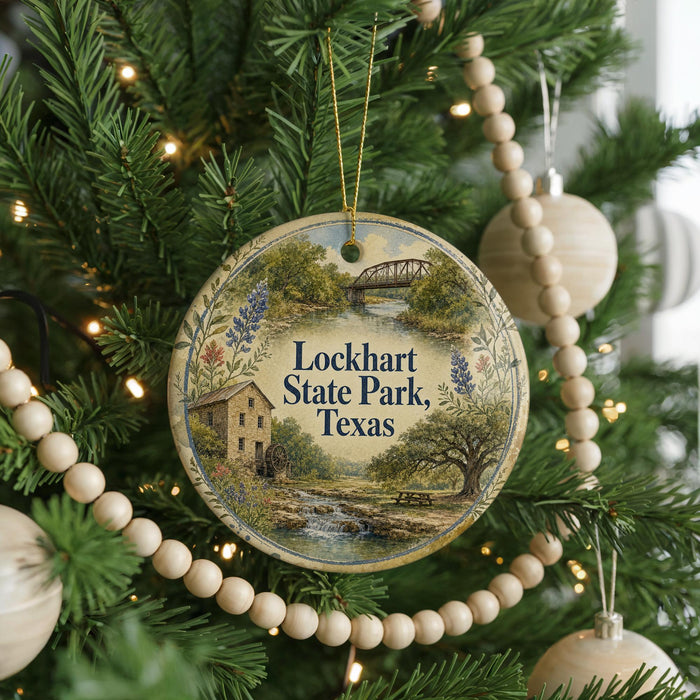 A round ornament hanging on a Christmas tree, featuring a scenic image of Lockhart State Park, Texas.