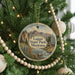 A round ornament hanging on a Christmas tree, featuring a scenic landscape of mountains, trees, and a river.