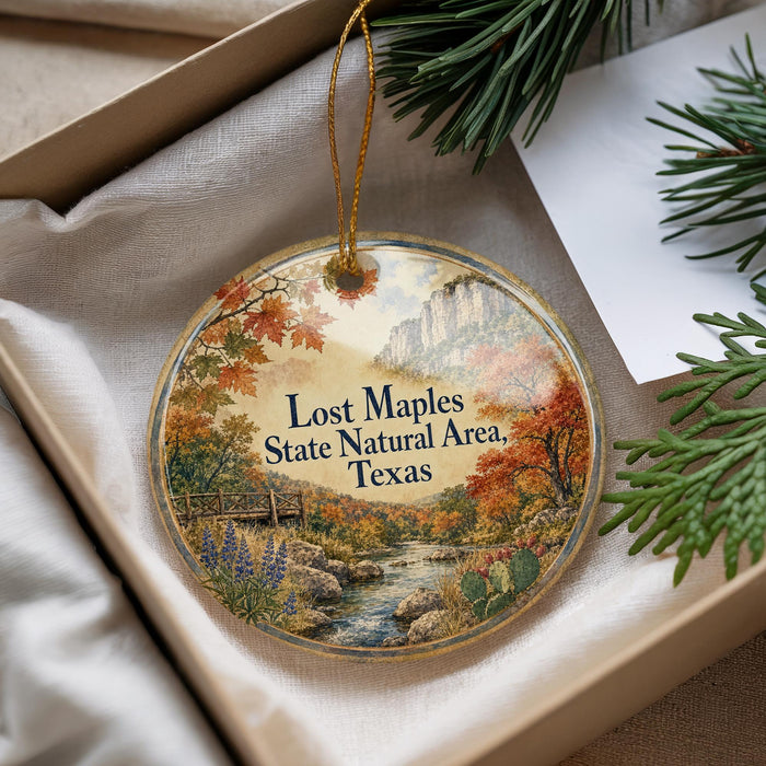 A decorative ornament with a scenic landscape of a river, mountains, and fall foliage, along with the text "Lost Maples State Natural Area, Texas".