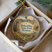 A decorative ornament in a box, featuring an illustration of Makoshka State Park in Montana.