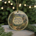 A round ornament with a scenic mountain landscape and a deer, hanging on a string.