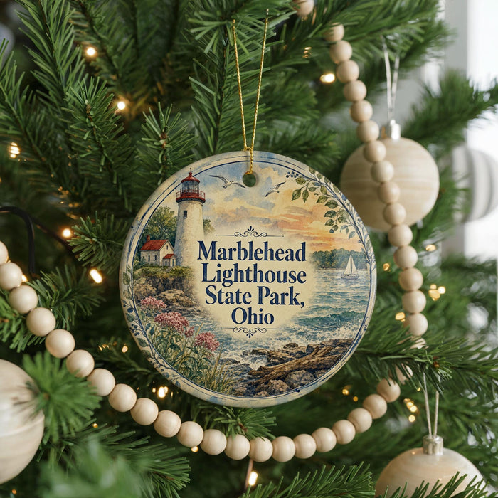 A round ornament hanging on a Christmas tree, featuring a lighthouse and a scenic landscape.