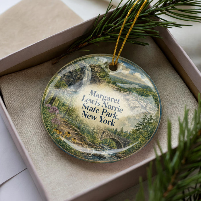 A decorative ornament in a box, featuring a scenic landscape with a waterfall and pine trees.