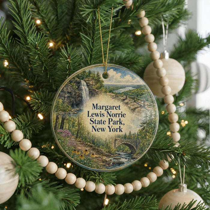 A round ornament hanging on a Christmas tree, featuring a scenic landscape with a waterfall and a bridge.