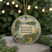 A round ornament with a scenic landscape of marsh creek, state park, and Pennsylvania, featuring a bird and a sailboat, is displayed on a table with a blurred background of a Christmas tree and lights.