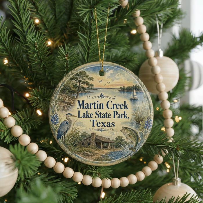 A round ornament hanging on a Christmas tree, featuring a scenic image of Martin Creek Lake State Park, Texas.