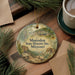 A circular ornament with a painting of a historic site, specifically Mastodon State Historic Site, Missouri, hanging on a wooden surface.