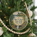 A round ornament on a Christmas tree, featuring a scenic image of a park with a waterfall and a bird perched on a tree branch.