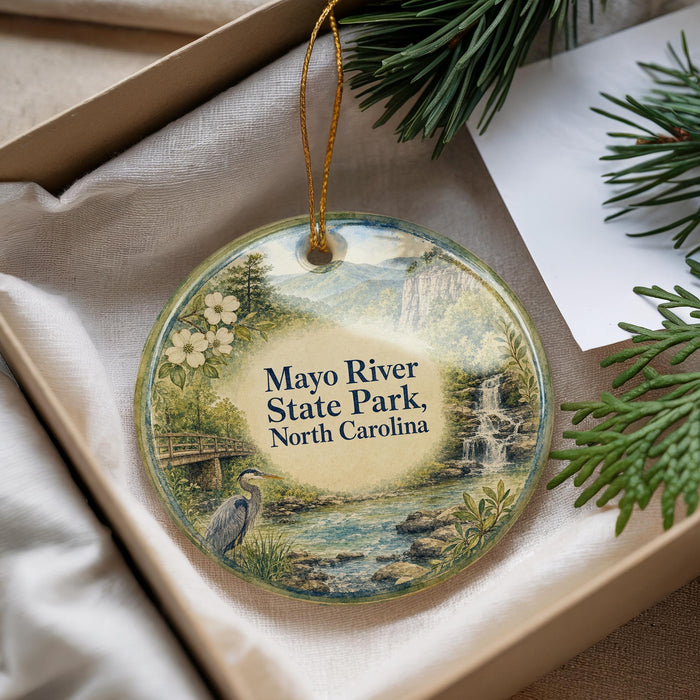 A round ornament with a scenic image of the Mayo River State Park in North Carolina, featuring a bird, a waterfall, and a bridge.