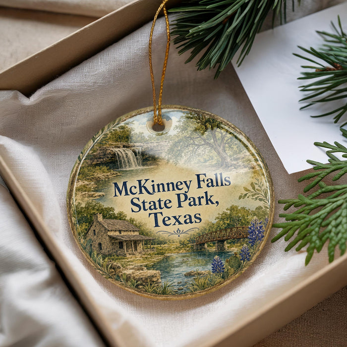A decorative ornament with a scenic image of McKinney Falls State Park, Texas, hanging from a string.