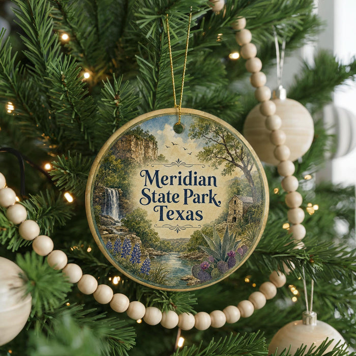A round ornament hanging on a Christmas tree, featuring a scenic landscape with a waterfall, pine trees, and a river.