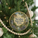 A round ornament hanging on a Christmas tree, featuring a scenic landscape with a waterfall, pine trees, and a river.