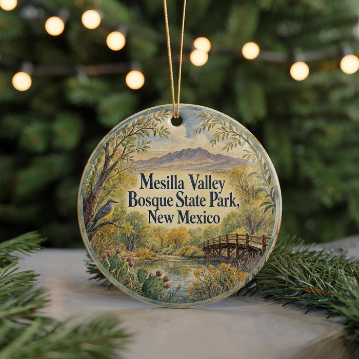 A round ornament with a scenic landscape of Mesilla Valley, Bosque State Park, New Mexico, featuring a bridge, trees, and mountains.