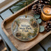 A wooden tray with a decorative ornament featuring a scenic image of Millsite State Park, Utah, and pine cones.