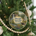 A round ornament hanging on a Christmas tree, featuring a scenic landscape with a waterfall and pine trees.