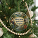 A round ornament hanging on a Christmas tree, featuring a woman in a blue dress and a scenic landscape with mountains and a bridge.