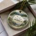 A decorative ornament with a scenic landscape of mountains, trees, and a body of water, featuring the text "Moran State Park, Washington" on it.
