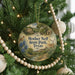A Christmas tree decorated with ornaments, including a circular ornament with a scenic image of Mother Neff State Park, Texas.