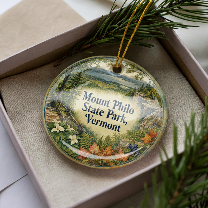 A decorative ornament in a box, featuring a scenic landscape of Mount Philo State Park in Vermont.
