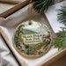 A decorative ornament with a scenic landscape of Mount Pisgah State Park, Pennsylvania, featuring a winding path, a waterfall, and pine trees.